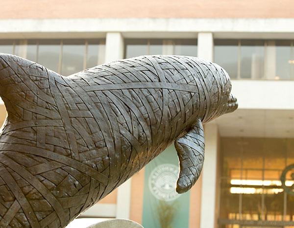 One of the dolphin statues with the Howard Administration Building in the background.